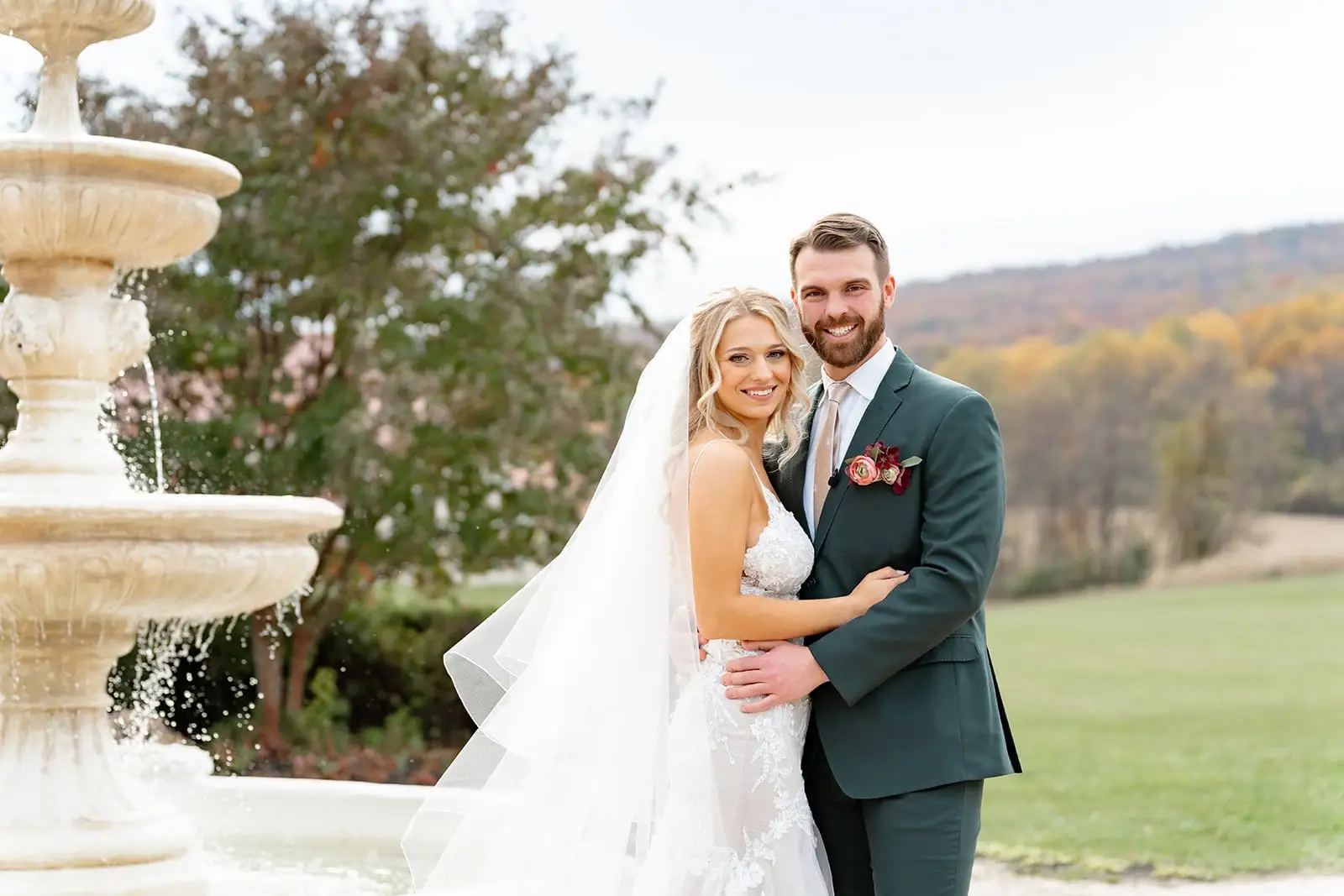 Jake and Casey by a stone fountain with autumn hills behind them