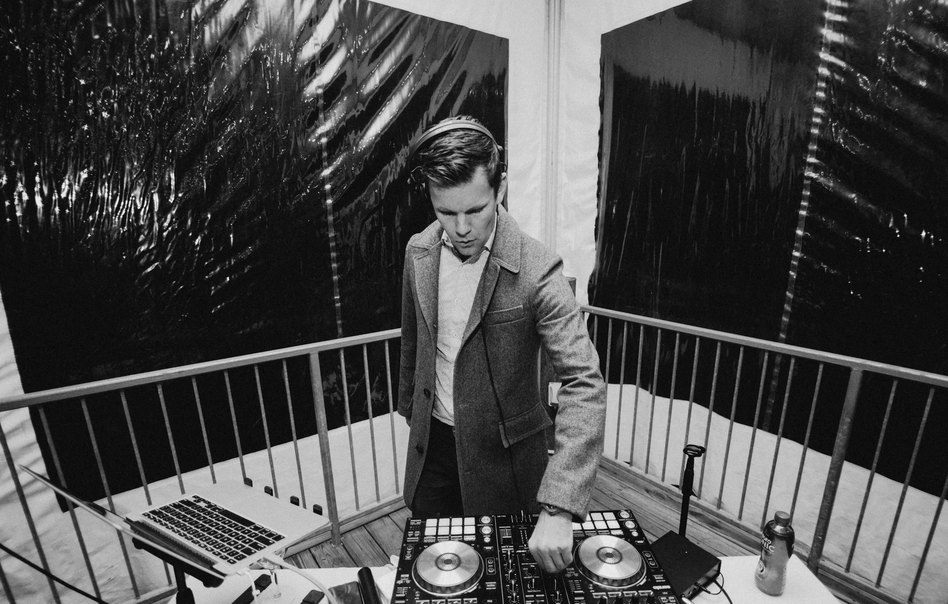 A DJ setting up his decks on a rooftop, in black and white