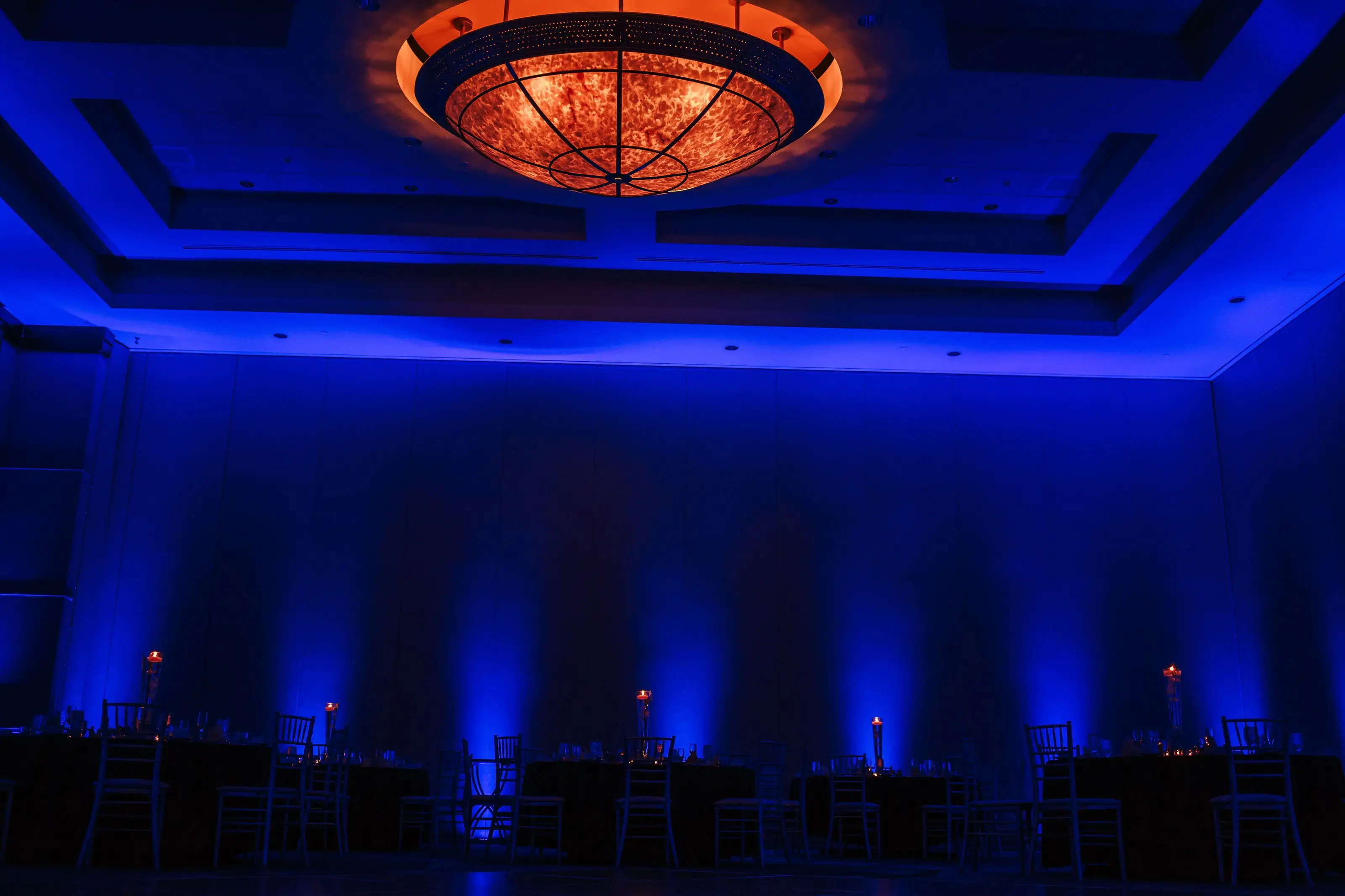 A ballroom washed in deep blue uplighting before the guests arrive